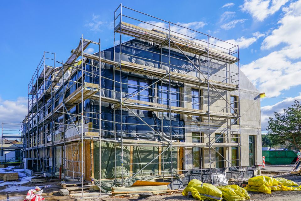 Ein eingerüstetes Haus wird gedämmt.
