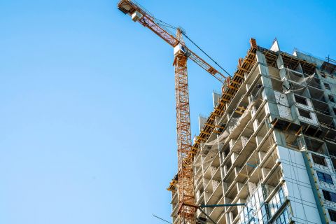 Ein im Bau befindliches Hochhaus, neben dem ein Kran steht.